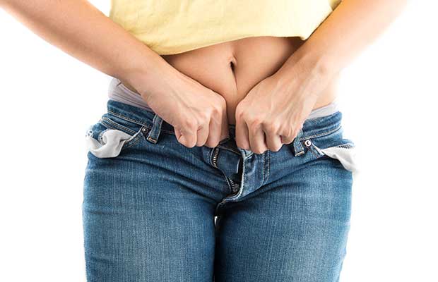 Femme essayant de boutonner jean